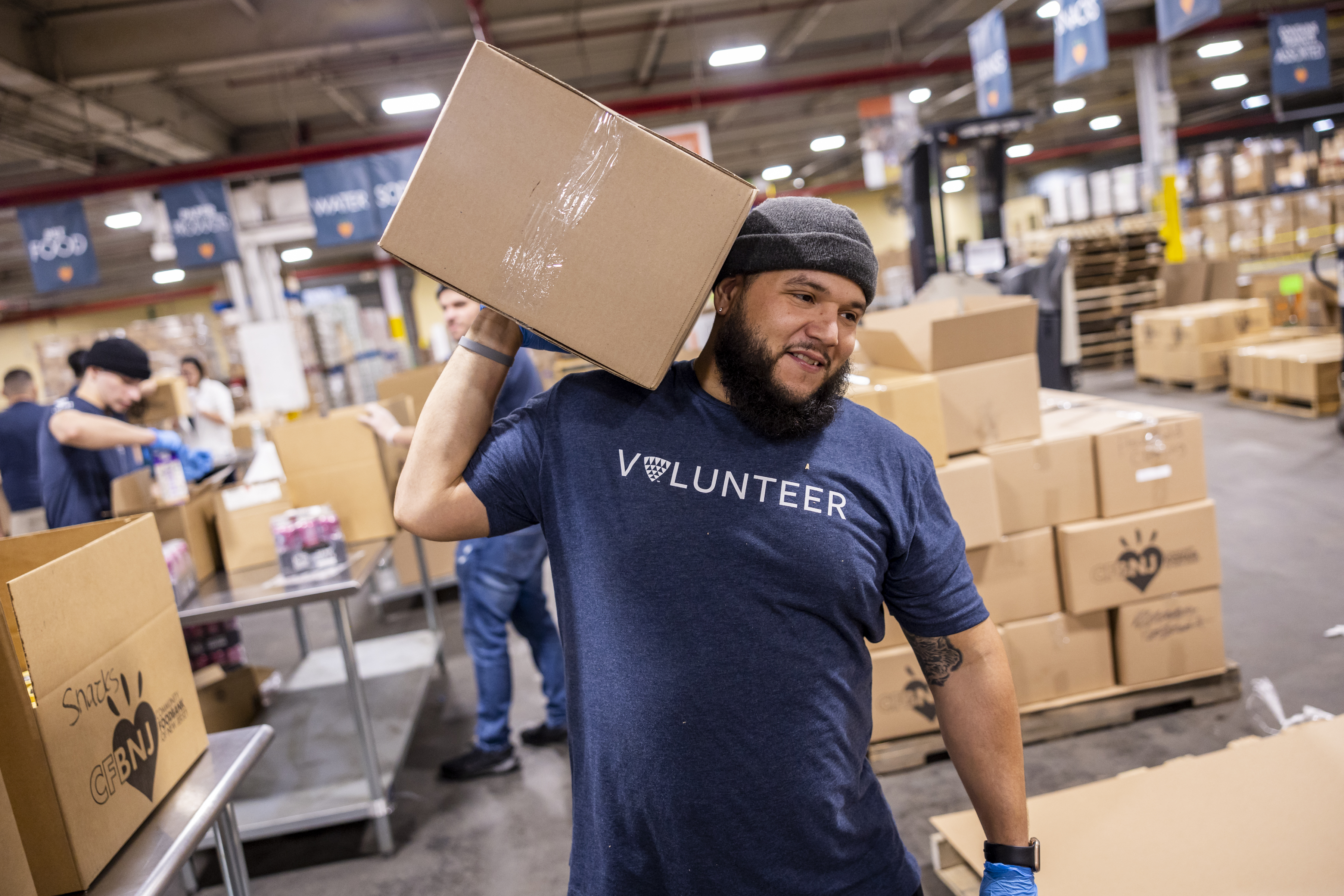 Man in Volunteer shirt living a box at a Foundation for Good event